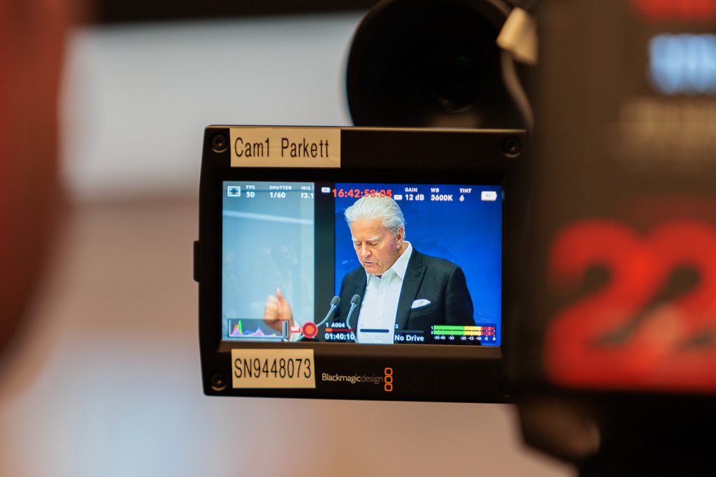 Fotografie einer Kamera die eine Pressekonferenz aufnimmt